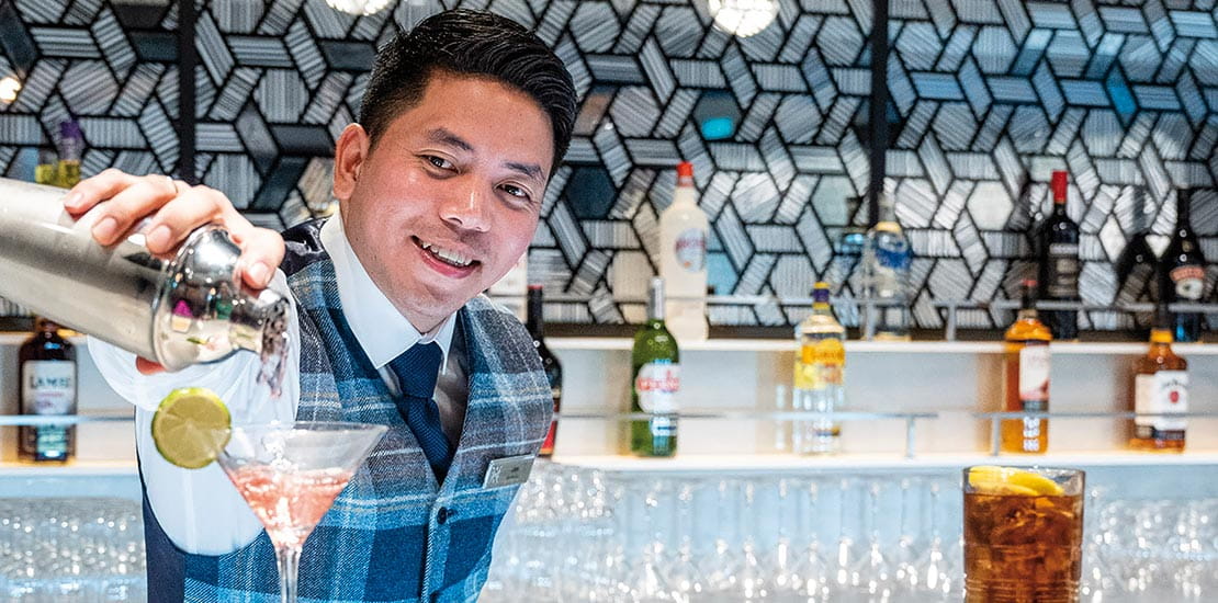 A bartender pouring a cocktail in the North Cape Bar on Spirit of Adventure